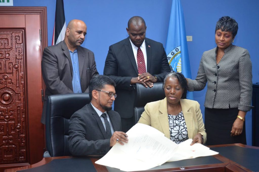 ExporTT Chairman Ashmeer Mohammed, seated at left, and Administrator in the Division of Community Development, Cherryl-Ann Solomon, sign a Memorandum of Understanding  on creating opportunities for local businesses at the Division’s conference room on Friday.  Standing, from left, are Dietrich Guichard, Chief Executive Officer - ExporTT,  Assistant Secretary in th Division, Shomari Hector and Manager of the Business Development Unit,  Shelly-Ann Baptiste.