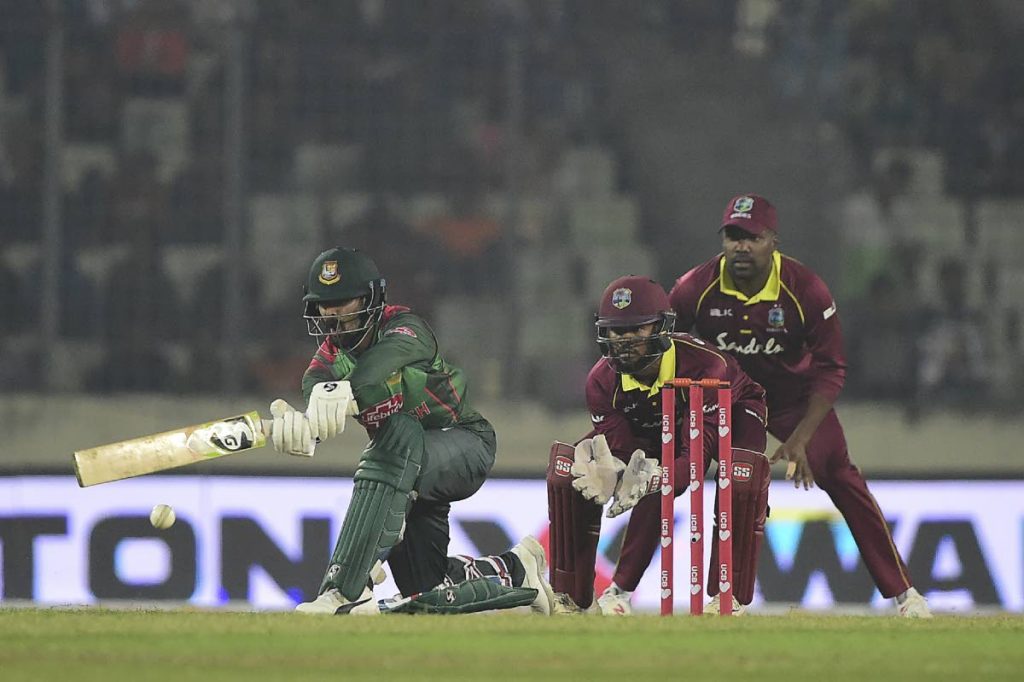 Bangladesh cricketer Liton Das (L) plays a shot as the West Indies cricketer Shai Hope (C) and Darren Bravo (R) looks on during the first One Day International (ODI) between Bangladesh and West Indies at the Sher-e-Bangla National Cricket Stadium in Dhaka on December 9, 2018. (Photo by MUNIR UZ ZAMAN / AFP)