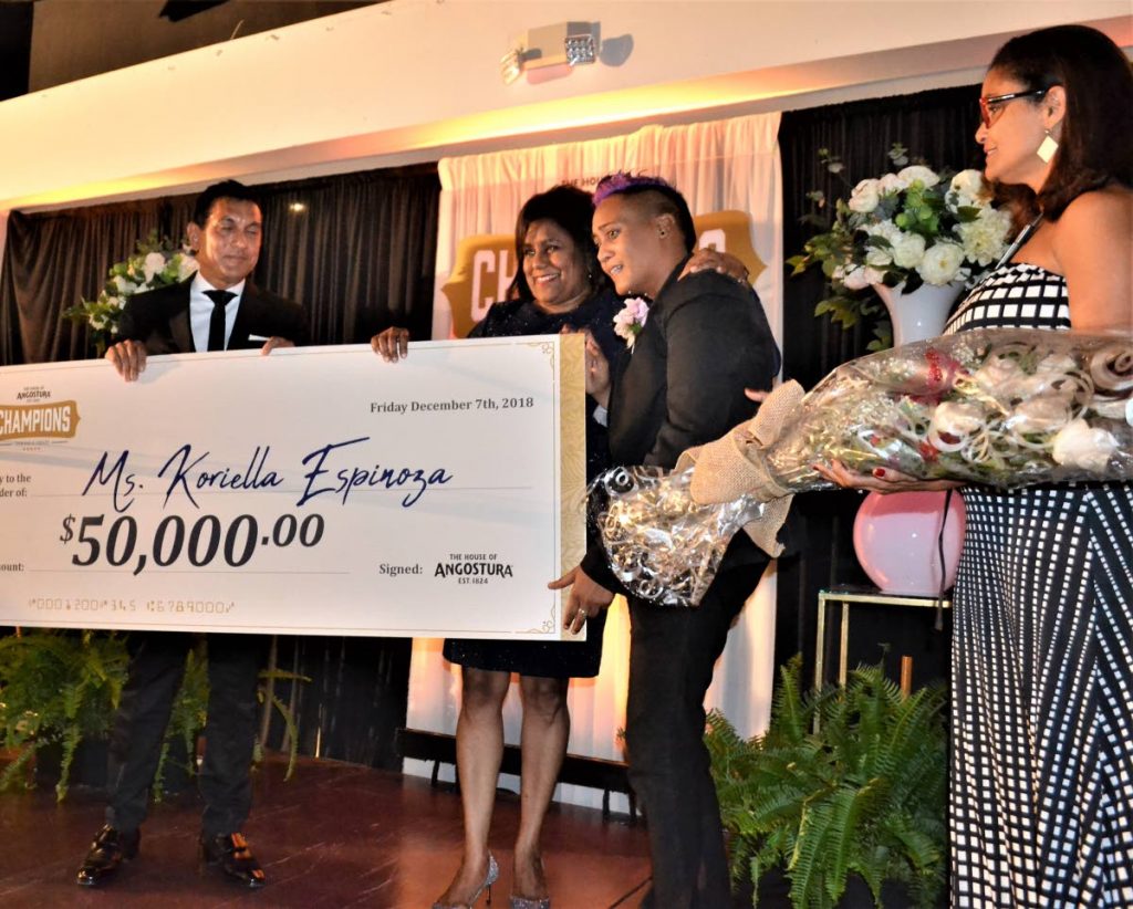 Angostura chairman Terrence Bharath and Minister of Trade Paula Gopee-Scoon present Koriella Espinoza with her cheque as Giselle La Ronde West waits to present her with a bouquet of flowers.