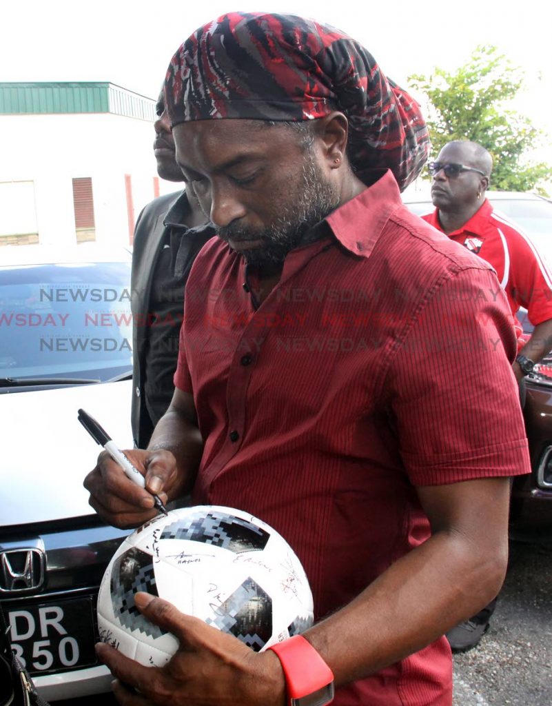 Former national footballer Arnold Dwarika signs a football in honour of ex-TT goalie Michael McComie at his funeral at Holy Cross Chapel, Arima, yesterday.