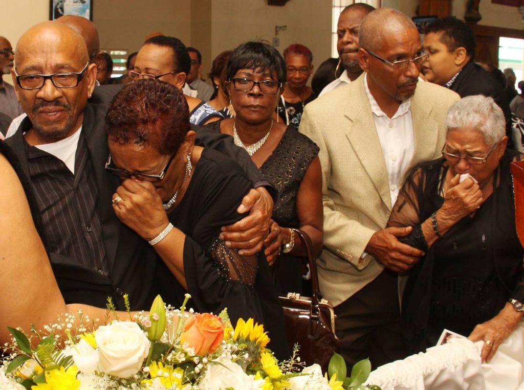 A TIME TO MOURN: Relatives of local music business icon Cleve Calderon including his wife Josephine, 2nd from left, and mother Phyllis, right, at his funeral yesterday at the Santa Rose RC Church in Arima.