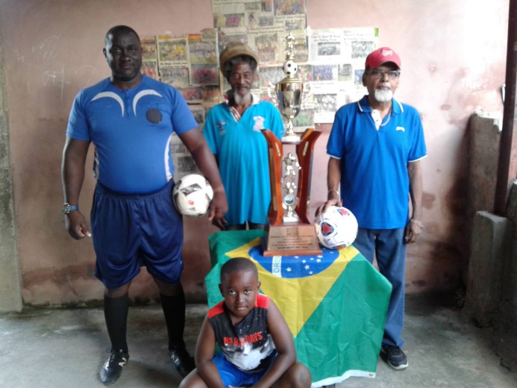 Fishing Pond Football League organiser Prakash Ramkissoon, right, with referees Shawn Brewster, left, and Andrew Joseph, as well as a young supporter.