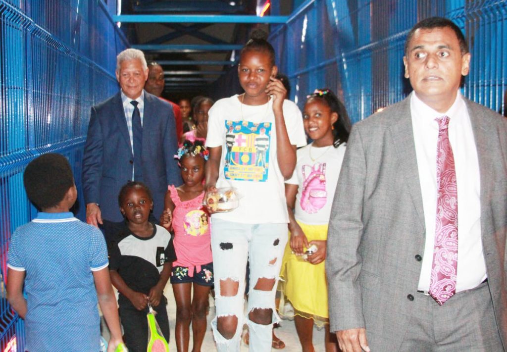 Works and Transport Minister Rohan Sinanan, right, leads children as well as Port of Spain Mayor Joel Martinez across the new walkover at Sea Lots which opened on Friday night. PHOTO BY ENRIQUE ASSOON 