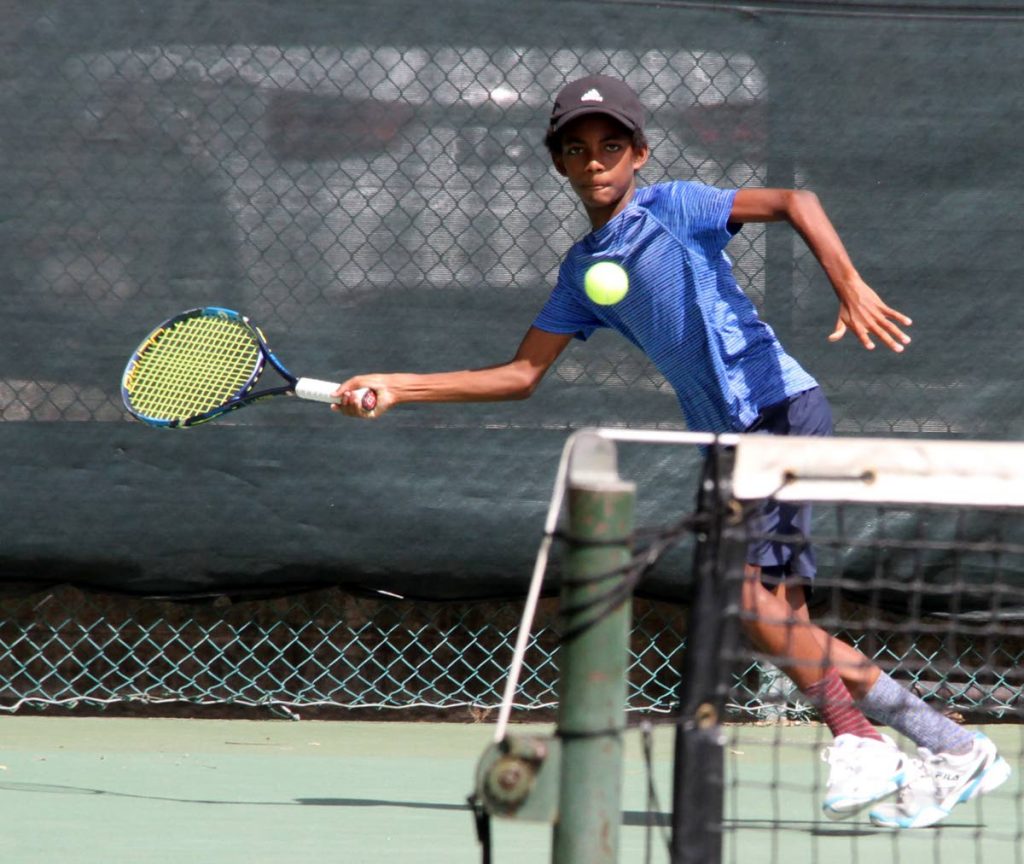 Luca Denoon stretches for the ball, in a Boys Under 14 match, during action at the Country Club, Maraval, for the RBC Junior Tennis Tournament,yesterday.