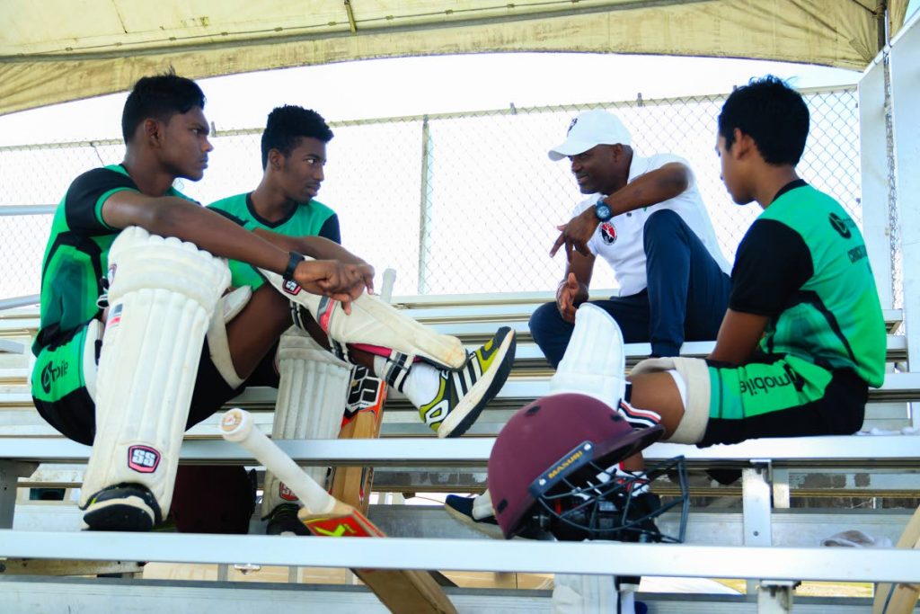 Youngsters of the bMobile Cricket Academy keenly listen to the advice of cricket legend Brian Lara, on December 8, at the  National Cricket Centre, Couva.