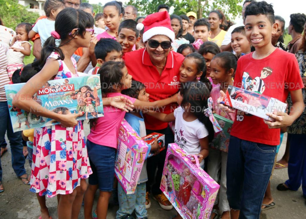 SANTA KAMLA: Happy children from Rochard Road in Barrackpore hug Opposition Leader Kamla Persad-Bissessar, who stood in for Santa Claus, and delivered toys to the children yesterday. PHOTO BY ANSEL JEBODH