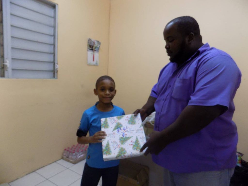 Cpl Dwayne John, right, of the Port of Spain City Police gives a present to 7-year-old Giovanni McShine at a Christmas Party at the Central Market on Sunday.  Photo by Shane Superville
