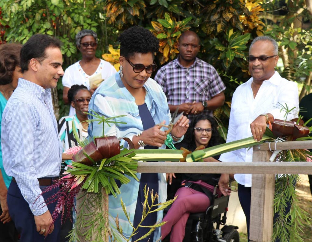 President Paula-Mae Weekes  opens the boardwalk by cutting an organic gathering of fruits and plants found at the Pointe-a-Pierre Wild Fowl Trust. Looking on are Dr Sterling Frost,  Robert Green and Shamla Maharaj.