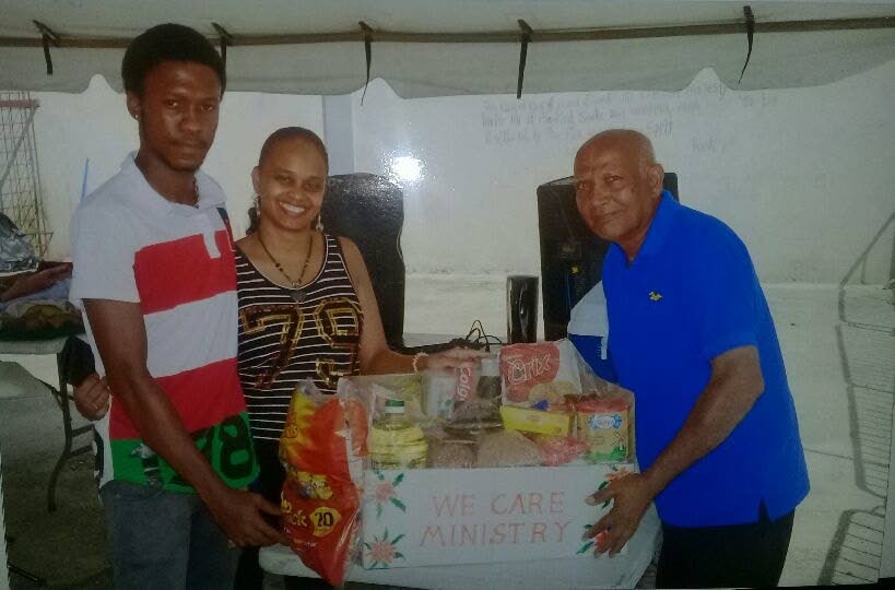 Sangre Grande businessman and preacher Mohan Narine presents a hamper to two residents during a recent distribution drive in the area.