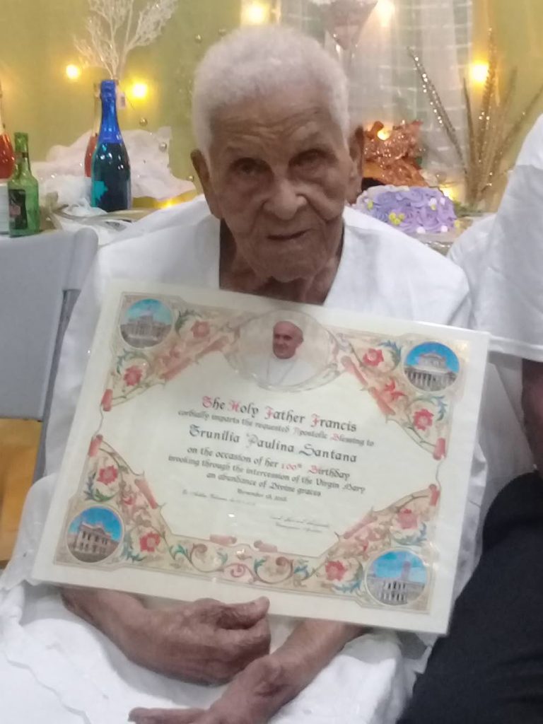 
Centenarian Trunilia Paulina Santana holds up the apostolic blessing she received from Pope Francis for her 100th birthday and her years of dedication and service to the Roman Catholic Church.