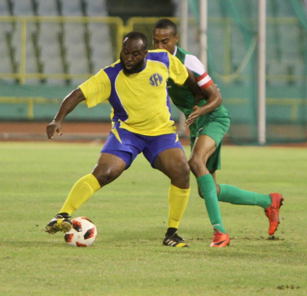 St Francois Nationals' Odelle Armstrong looks to make a play while holding off Cantaro FC's Kern Mieres is the NFA FA Cup final at the Hasely Crawford Stadium, Mucurapo, Wednesday. 