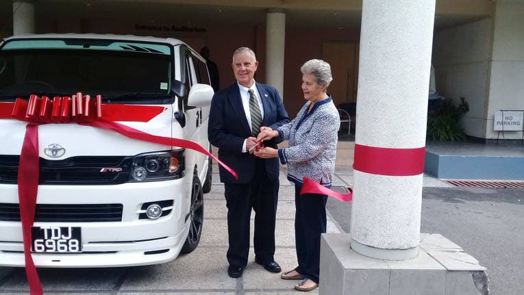 GREAT CUT: US Ambassador to TT Joseph Mondello (left) and Living Water Community co-founder Rhonda Maingot cut a ribbon on a ten-seater bus donated from the embassy to Living Water yesterday at a ceremony held at St Finbar's Church, Diego Martin. 