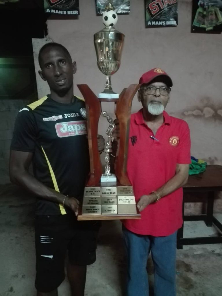 Gremio manager Ashky Charles, left, winner of the Caribbean Welders Fishing Pond Football League collects the trophy from organiser Prakash Ramkissoon.