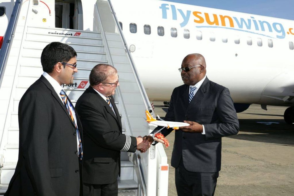 Chief Secretary Kelvin Charles, right, receives a miniature plane from pilots of Sunwing Airlines flight WG175, Marty Neel and Blair Pritchard, at the ANR Robinson International Airport last Thursday. (TTAL Photo)