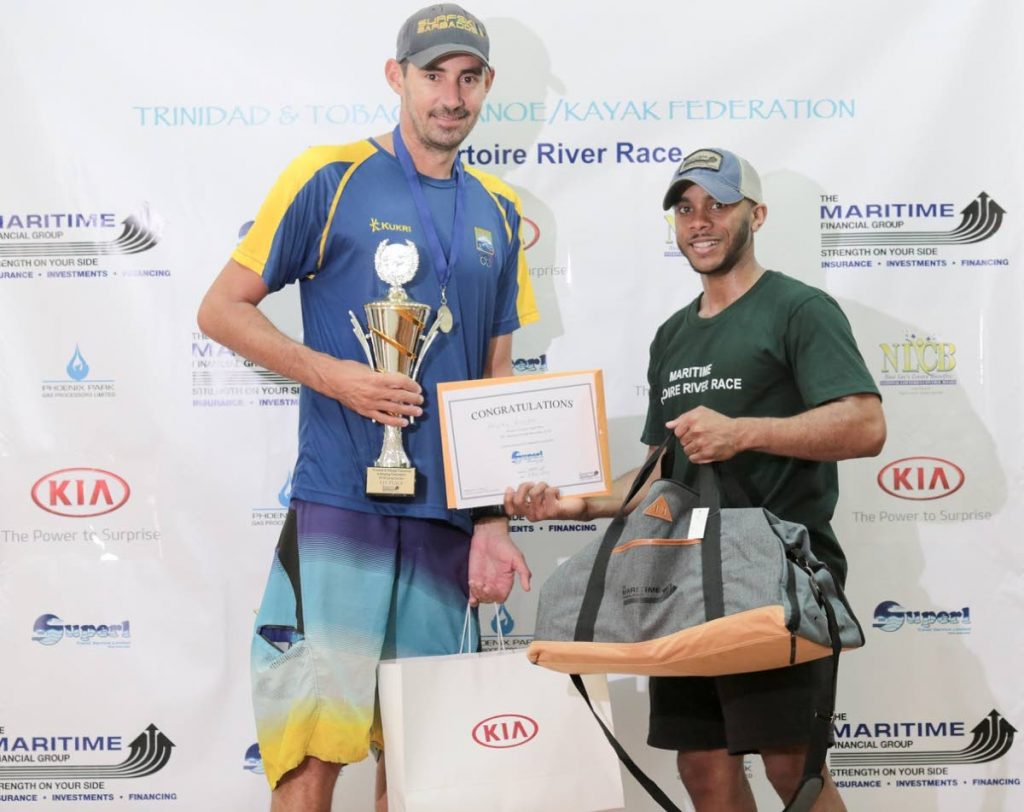 Stanley Brooker of Barbados, left, collects his trophy and prize after winning the Maritime Ortoire River Race long course division. 