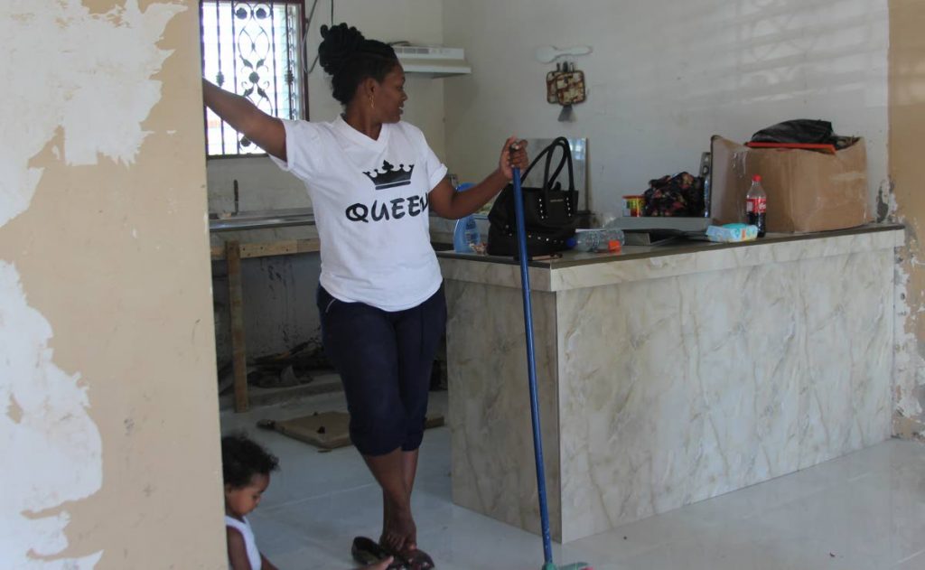 A resident of Greenvale stops cleaning to survey the unfinished work done by contractors in her kitchen as her child sits next to her yesterday.