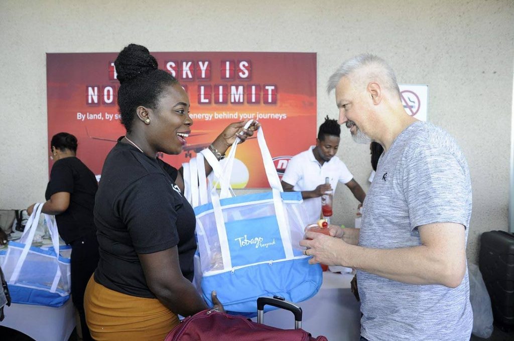 Tobago Tourism Agency Limited’s Marketing Officer Andra Joefield presents a passenger from Sunwing Airlines inaugural Toronto to Tobago flight with a “Tobago Beyond” beach bag filled with local sweets.