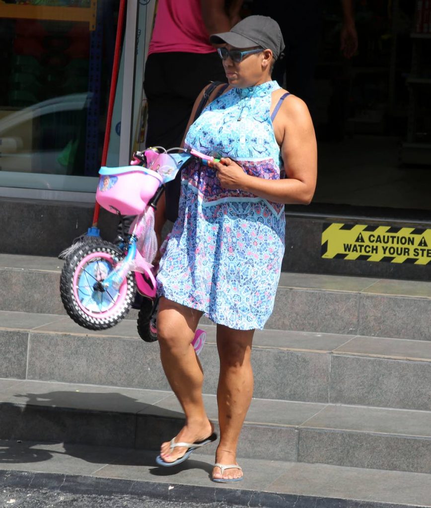 A shopper leaves Jay's Toy Box, St James Street, San Fernando with a child bike bought in yesterday's Boxing Day sale. 