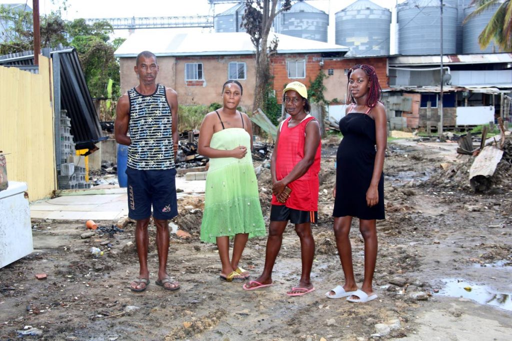 Anderson Ashton, from left, Kafie Noel, Velda Cadet and Angie John at the burnt-out site of their homes on Concerned Citizens Street, California yesterday. A fire on December 13 destroyed six houses leaving 19 people homeless.