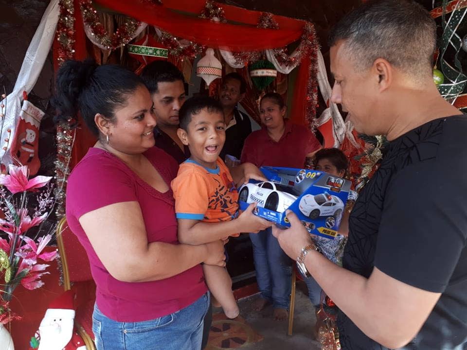 Police Commissioner Gary Griffith presents Mario Narine, held by his mother Sarika Dookie, with a toy police car during a visit to his home at Bissoon Trace, Fyzabad yesterday. PHOTO COURTESY TTPS