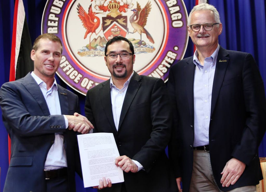 In this November 2018 file photo, Sandals group deputy chairman Adam Stewart and Minister of Communications Stuart Young  hold a copy of the MoU between the Government and Sandals for the construction of a resort in Tobago. Looking on is Sandals CEO Gebhard Rainer.