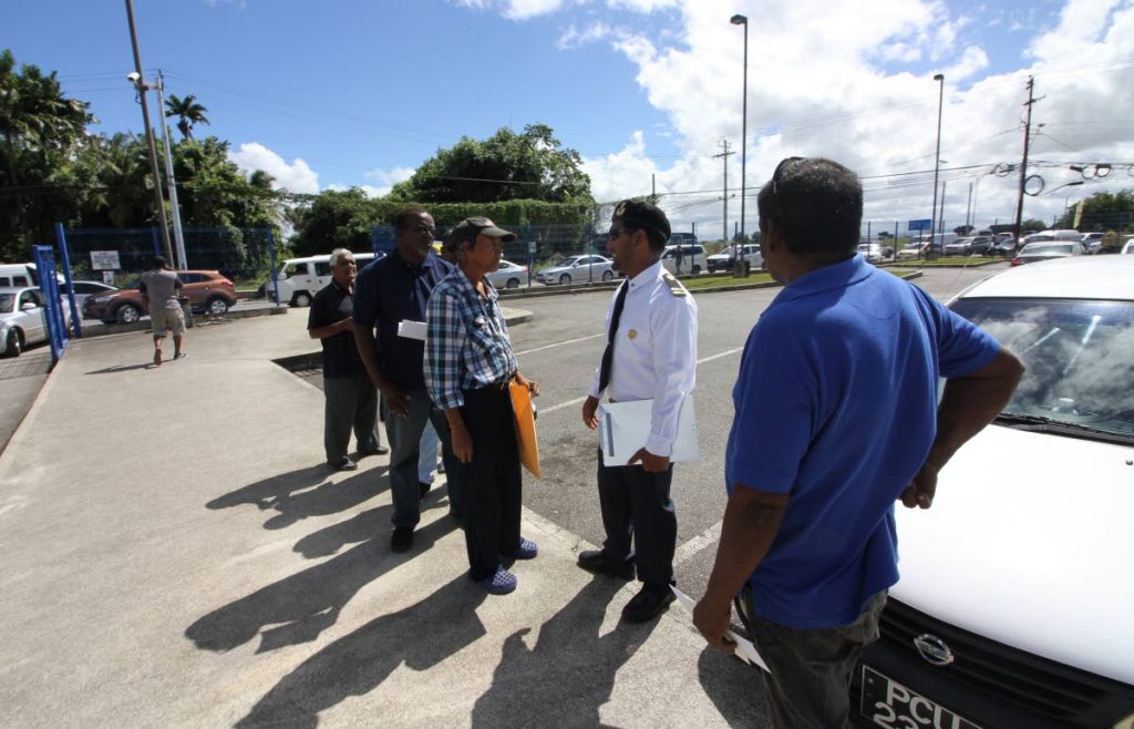 File photo: A Licensing Officer speaks with drivers waiting on their inspection certificate stickers at the Licensing Office in Caroni.