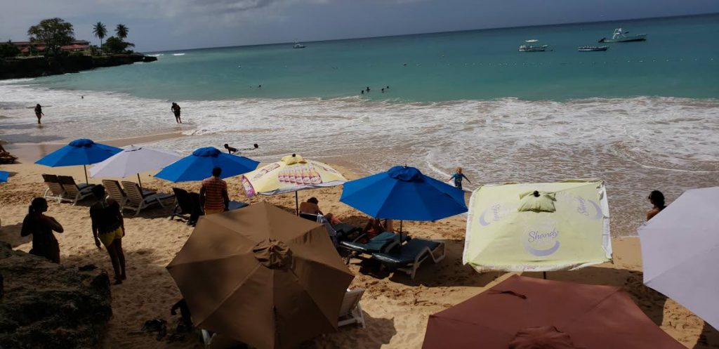 A handful of visitors are at Store Bay beach on Monday.