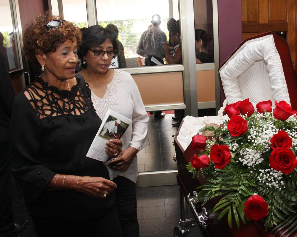 Farida Sanchez, left, looks at the body of her deceased companion Oliver Camps, at his funeral at St Finbar's RC Church, Diego Martin, yesterday. PHOTO BY ANGELO MARCELLE 
