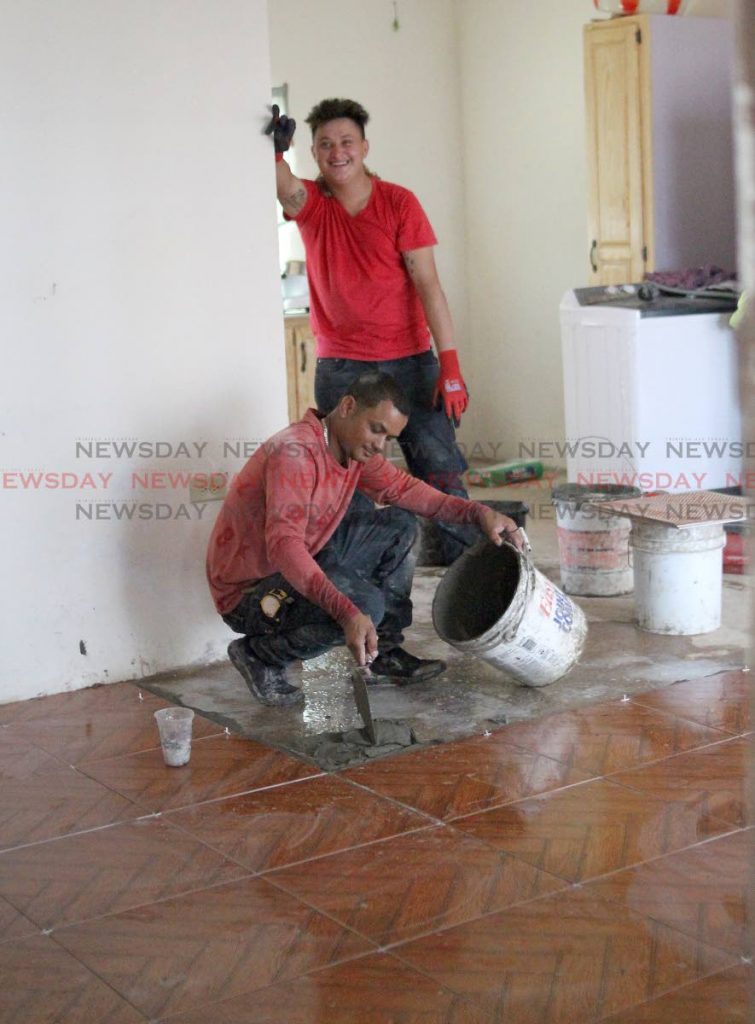 A work crew completes tile works in one of the Greenvale homes affected by devastating floods in October last year during an official tour of the area by HDC managing director Brent Lyons, and other technical staff on Thursday. PHOTO BY ROGER JACOB.