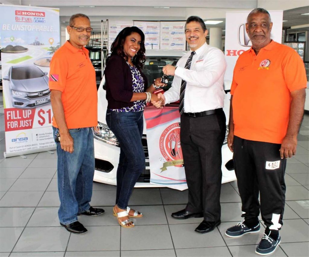 Shivaune Carter-Tam recieves her car keys from general manager  Daryl Young as Wayne Ragnauth, left, and Cleavland Garcia of the Woodbrook St James Association looks on.