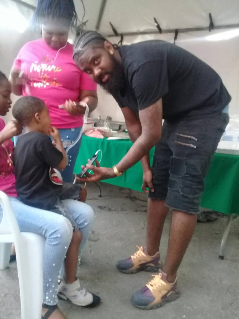 Barber Kendell Paul shares a light moment with his son  Kerdell during Tin Man’s New Image Barbershop’s recent customer appreciation day in Sangre Grande.