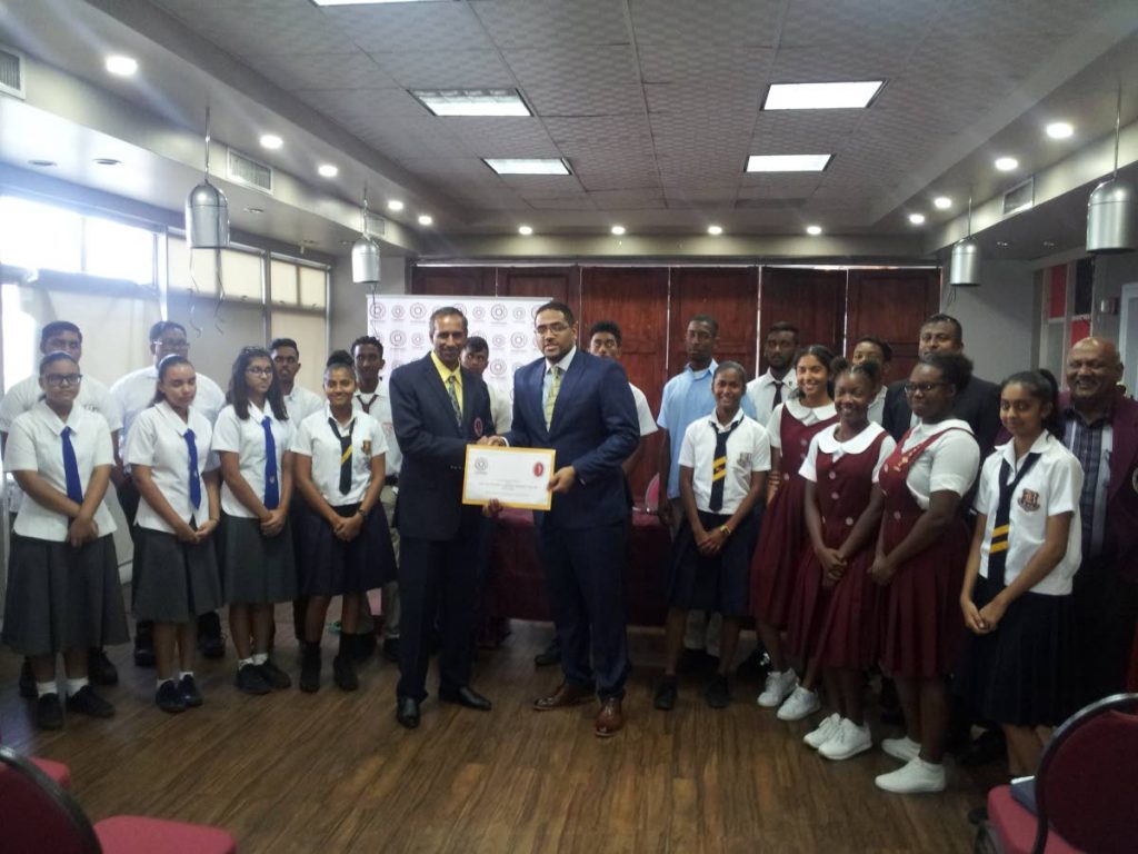 Francois Ottley of PowerGen, right, presents a cheque to SSCL president Surujdath Mahabir at the launch of the 2019 season, yesterday. Students who will be competing this year are also in the photograph.