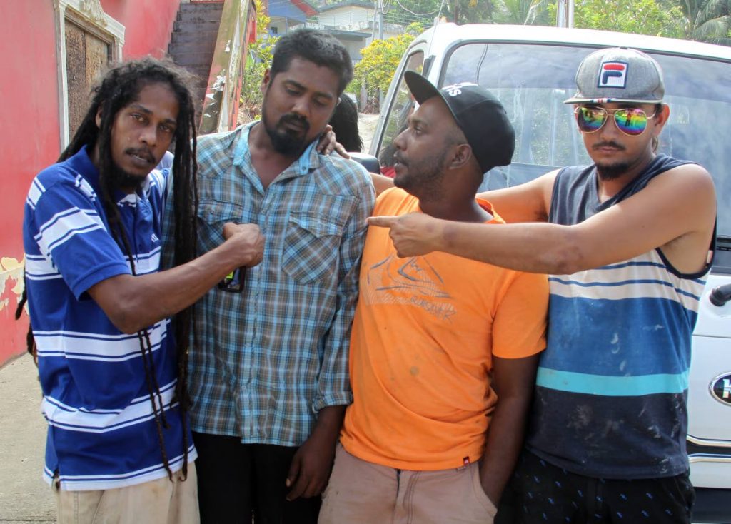 MOURNING: Kishon Kesam Ramnarine (second from left), who survived a boating mishap in which two of his fishing colleagues died at Maracas yesterday morning, is comforted by friends.   PHOTO BY ROGER JACOB