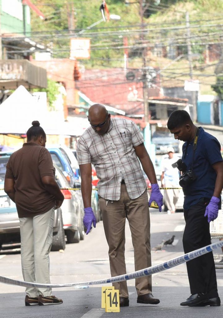 LOOK THERE: A policeman points to bullet casings strewn along Prince Street in Port of Spain following a shooting incident yesterday. PHOTO BY KERWIN PIERRE