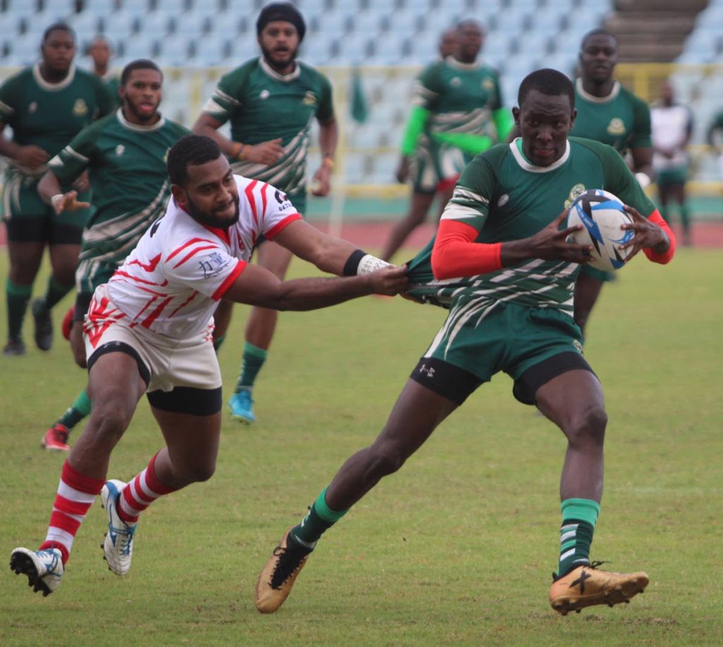 Harvard's Joseph Quashie, rights, looks to shake off the tackle of a Caribs opponent in a TT Rugby Football Union championship division clash last year. 