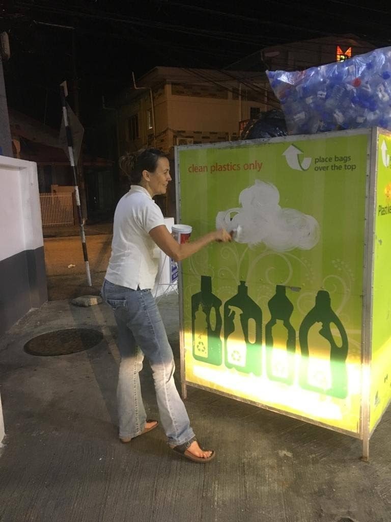PLASTIKEEP NO MORE: Plastikeep founder Rosanna Farmer paints over the Greenlight/Plastikeep logo on a recycling bin at Massy, Westmall as part of the shutdown of the project. 