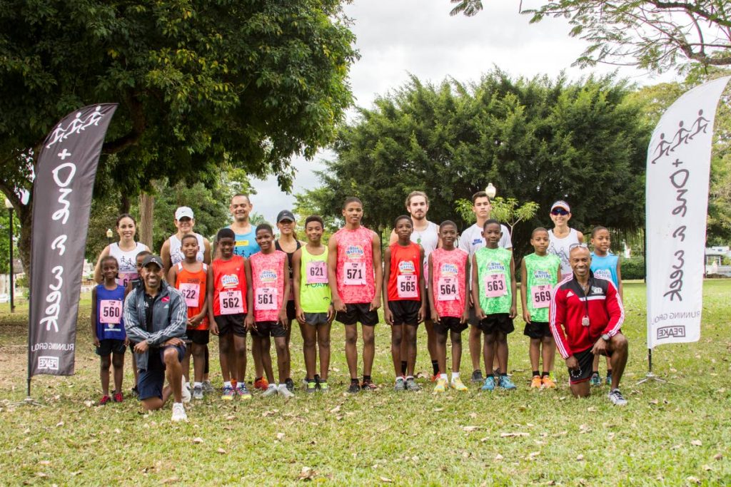 Young runners coached by Derrick Simon (kneeling left) pose before the start of the TTIM Kiss 5K on January 26, 2019 at Jackson Square, Port of Spain. At back left is administrator Rebeca Keung Fatt and kneeling at right is coach Dexter Simon.