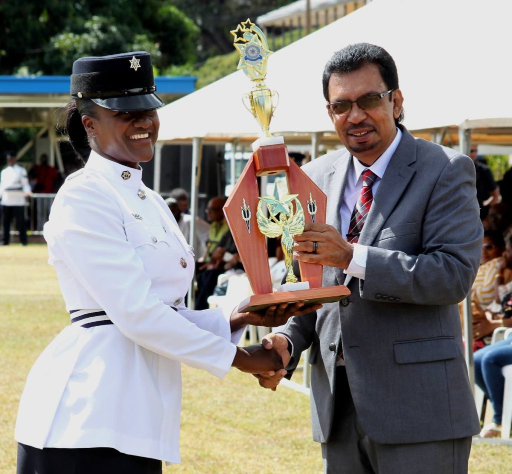 OUTSTANDING: Minister of Rural Development and Local Government Kazim Hosein presents WPC Sparkel Marchan with a trophy for being the most outstanding trainee during the passing-out parade for municipal police at the Police Academy, St James, on Saturday.