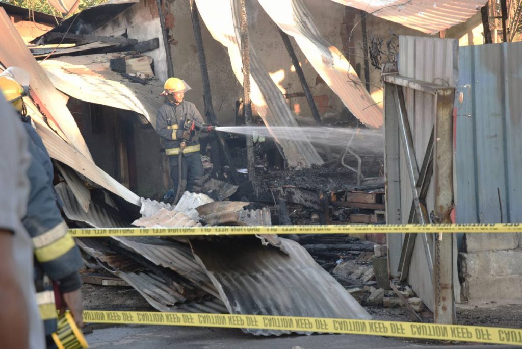 HOT WORK: A fireman douses remnants of a fire which yesterday destroyed this house in Sea Lots and claimed the life of a woman.