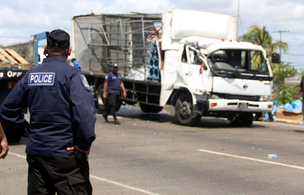 A policeman looks on at the scene of a collision involving a garbage truck, a Blue Waters truck and PTSC bus in which two women were killed on the Uriah Butler Highway, Chaguanas on February 5. PHOTO BY ANSEL JEBODH