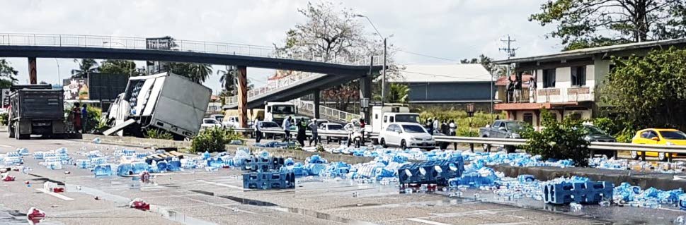 WATER BLOCKAGE: Cases of Blue Waters bottled water along the north-bound lanes of the Uriah Butler highway following an accident which claimed the lives of two women.