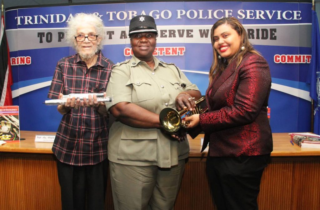 Legendary saxophonist Roy Cape, left, and Krystal Borris Bernard, music director of the Positive Movement Orchestra, right, present Assistant Commissioner of Police Patsy Joseph with a flute and trumpet respectively at the weekly police press briefing at the Police Administration Building yesterday. The instruments will then be handed over to the Oropune Police Youth Club.