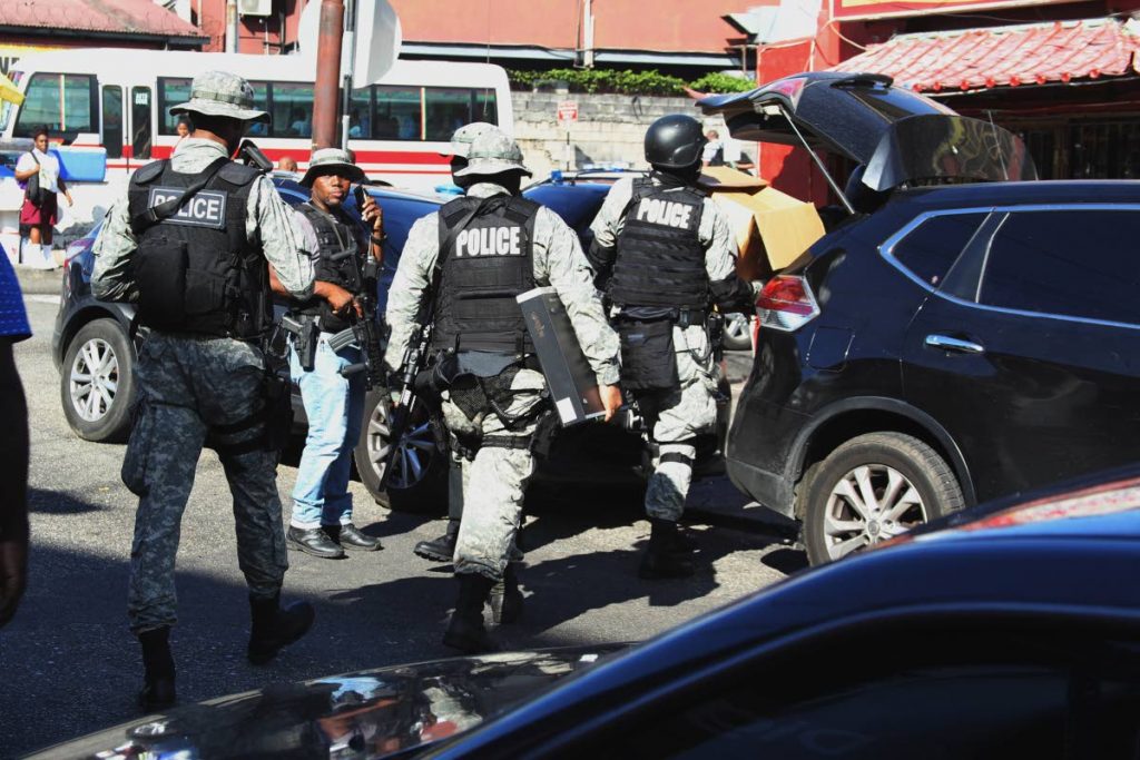 Members from the Special Operations Response Team, the Financial Intelligence Unit and Human Trafficking Unit, perform an extensive raid on Jamlong Members Club and JingDu Fast Food Resturant on Southern Main Road, Curepe, yesterday.