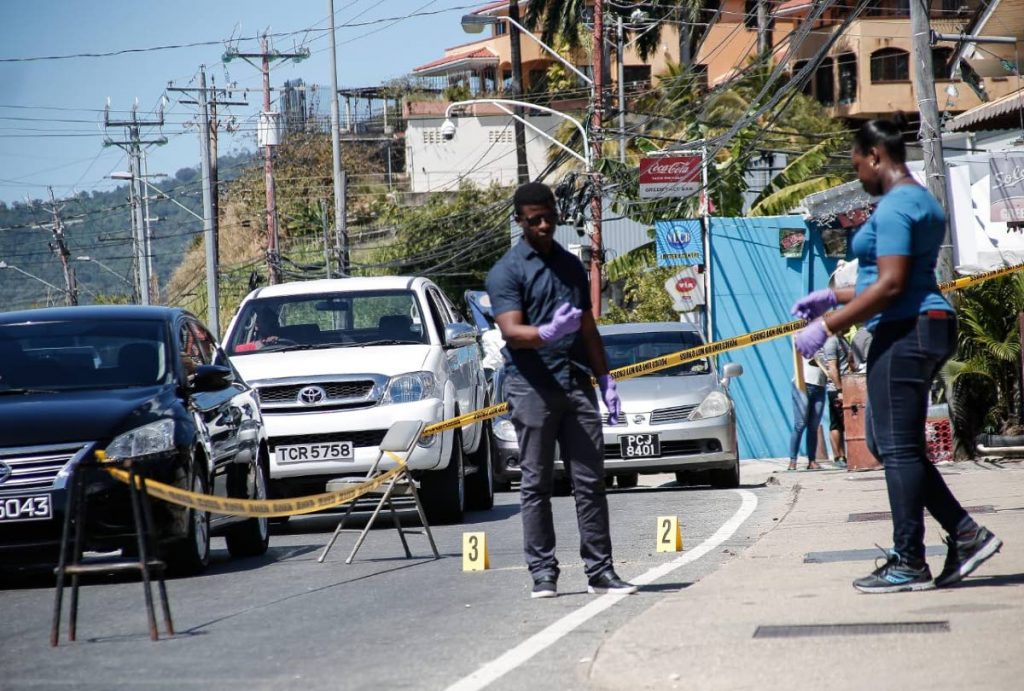 Investigators at the scene on Western Main Road, Caremange, near L'anse Mitan Road, where two women and an American teenage girl got shot while they were passengers in a car on Saturday morning. PHOTO BY JENSEN LA VENDE