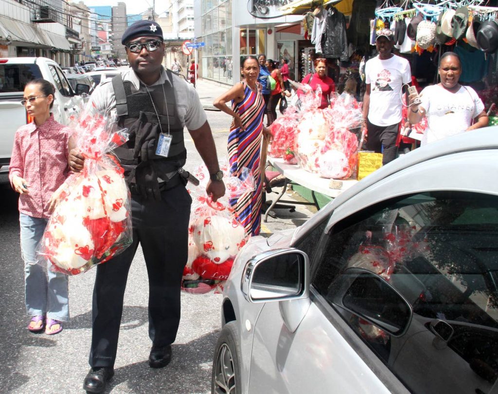 NO LOVE: A police officer leaves with Valentine’s Day items from a vendor on Queen Janelle Commissiong Street yesterday. PHOTO BY AYANNA KINSALE