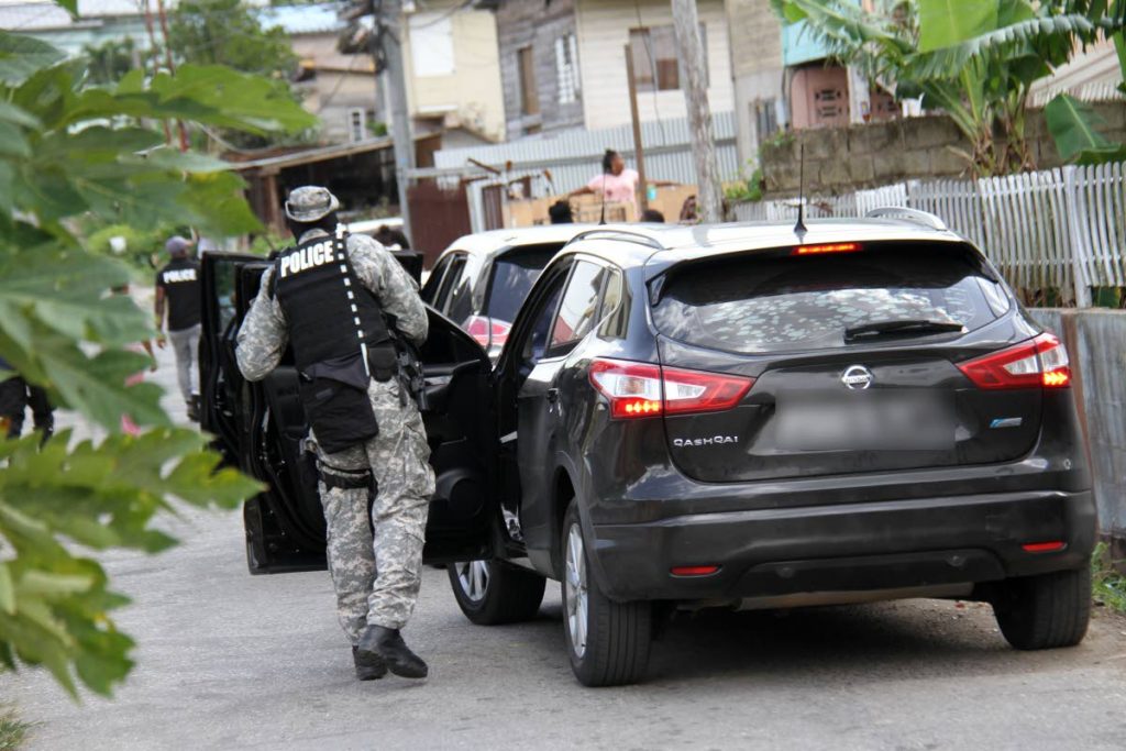 I REACH: A policeman arrives in La Romaine to join others in an anti-crime raid which later led to the arrest of 20 people and seizure of a number of illegal items. PHOTO BY CHEQUANA WHEELER