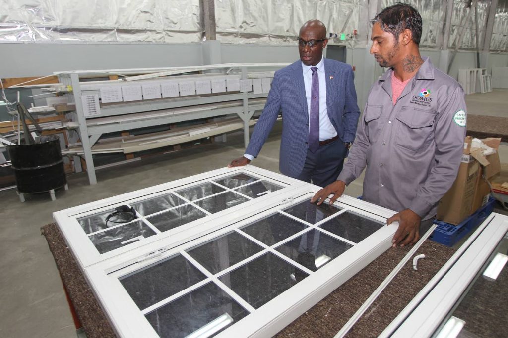 BUSINESS OPENING: Prime Minister Dr Keith Rowley looks at a window yesterday made by Domus Windows and Doors Ltd. PHOTO BY LINCOLN HOLDER
