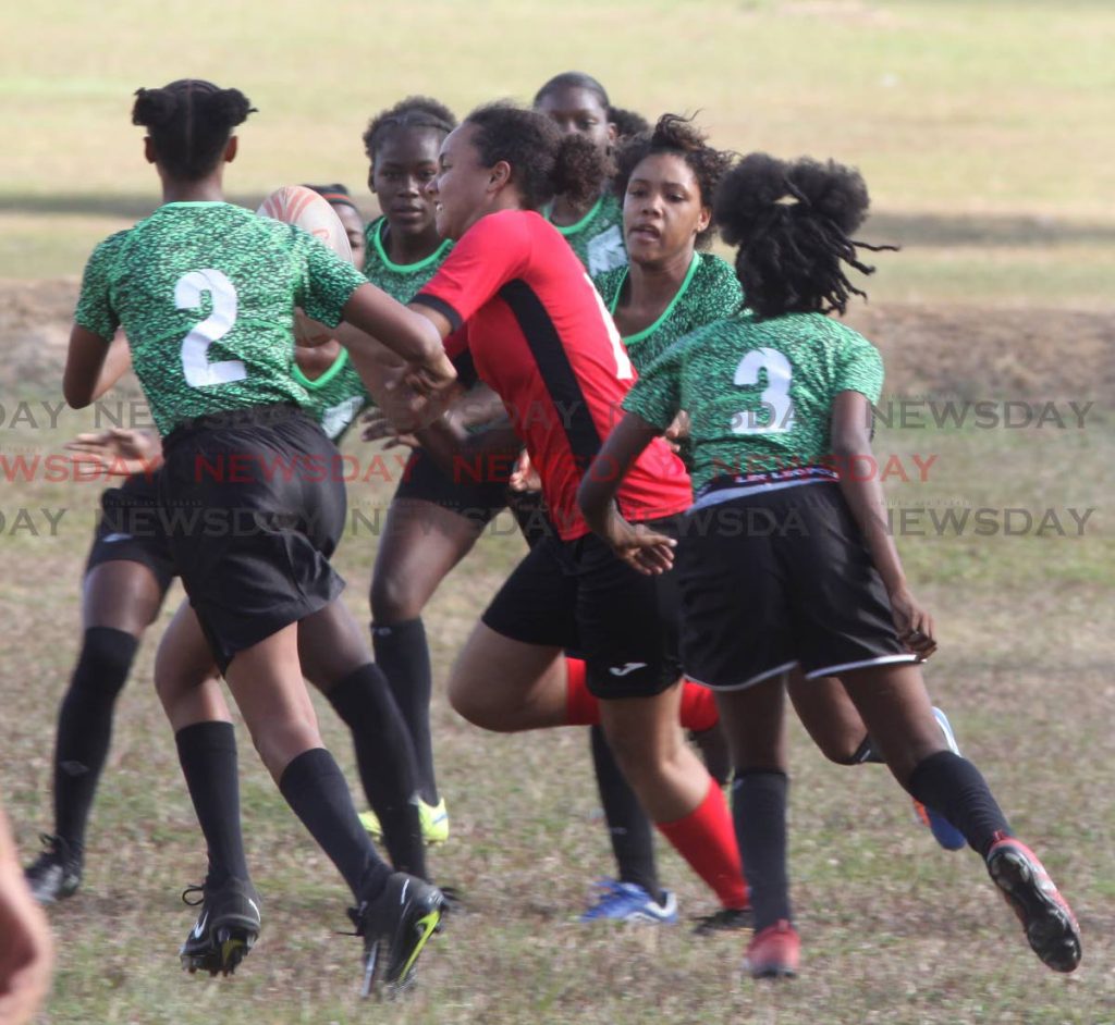 Bishop Anstey's Babi Oura is tackled by six San Juan North players in the Schools Girls Rugby League final yesterday at the Queen's Park Savannah, Port of Spain. PHOTO BY ANGELO MARCELLE 