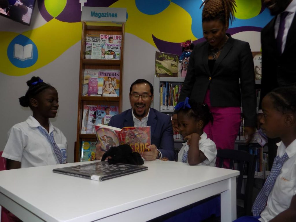 Minister of National Security Stuart Young, second from right, reads to children during the opening of the Beetham Community Library, Beetham Estate, yesterday morning, as Minister of Culture and the Arts Nyan Gadsby-Dolly looks on. 