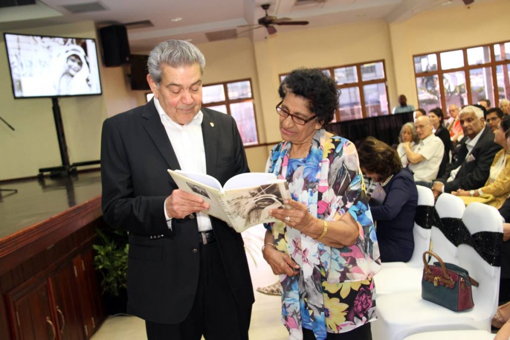 Dr George Laquis shows a copy of his book Call Me Pud to Zalayhar Hassanali at the books launch on February 28. 